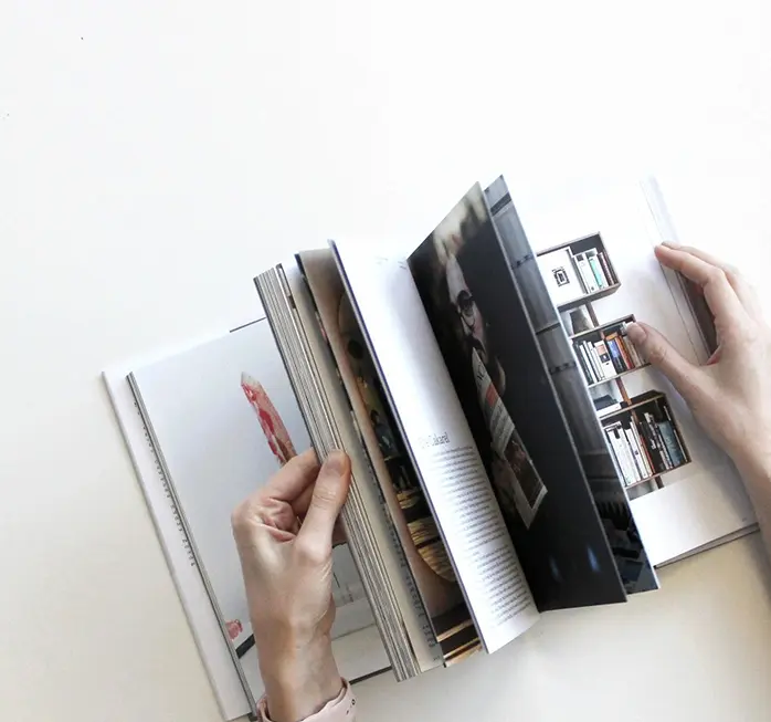 A person is holding open books on the table