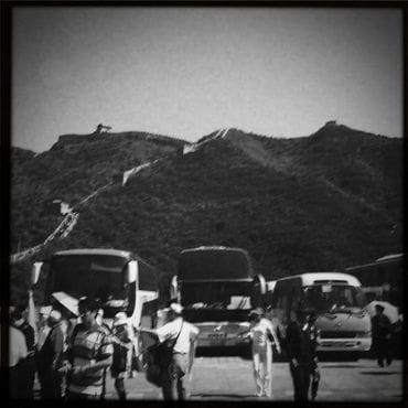 A group of people standing around parked buses.