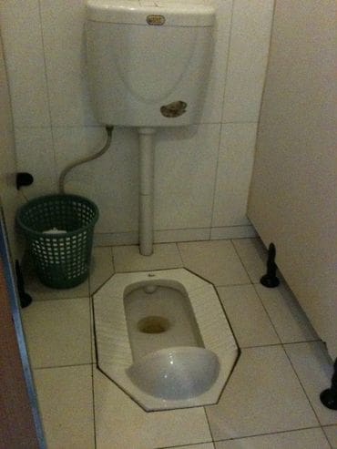 A toilet with the seat up and the urinal down.