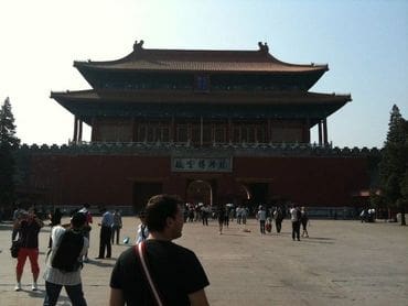 A group of people walking around in front of a building.