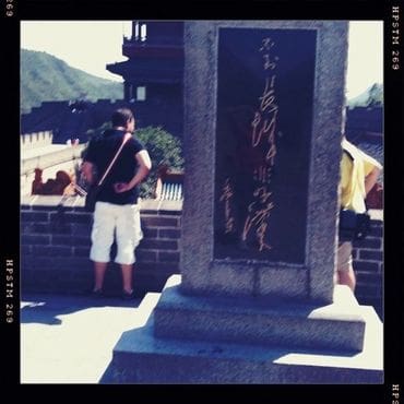 A man standing next to a stone wall.