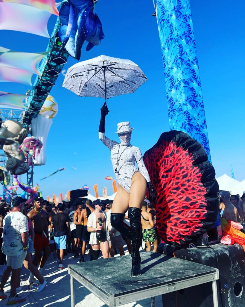 A person in white shirt and black boots holding an umbrella.