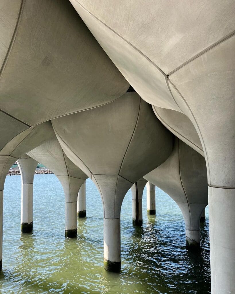 A view of the water from underneath an underside of a pier.