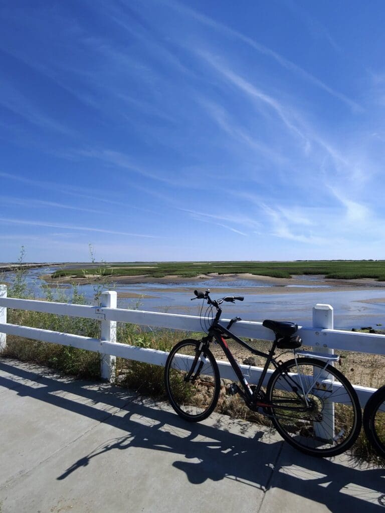 A bicycle parked on the side of a white fence.