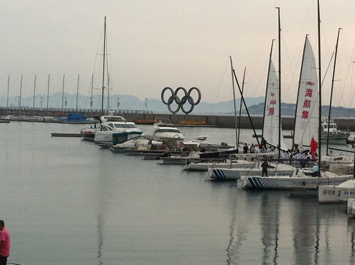 A group of boats in the water near some buildings.