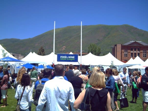 A crowd of people walking around tents on the grass.