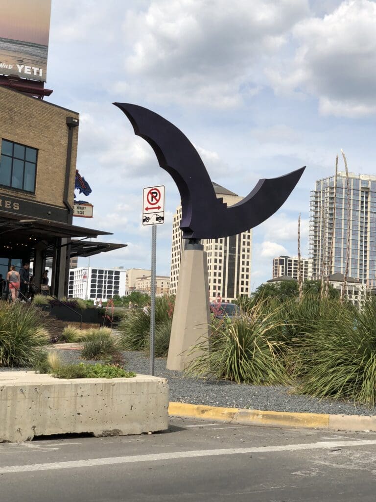 A bat sculpture in the middle of a city.