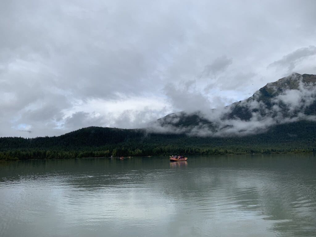 A boat is floating on the water near some mountains.