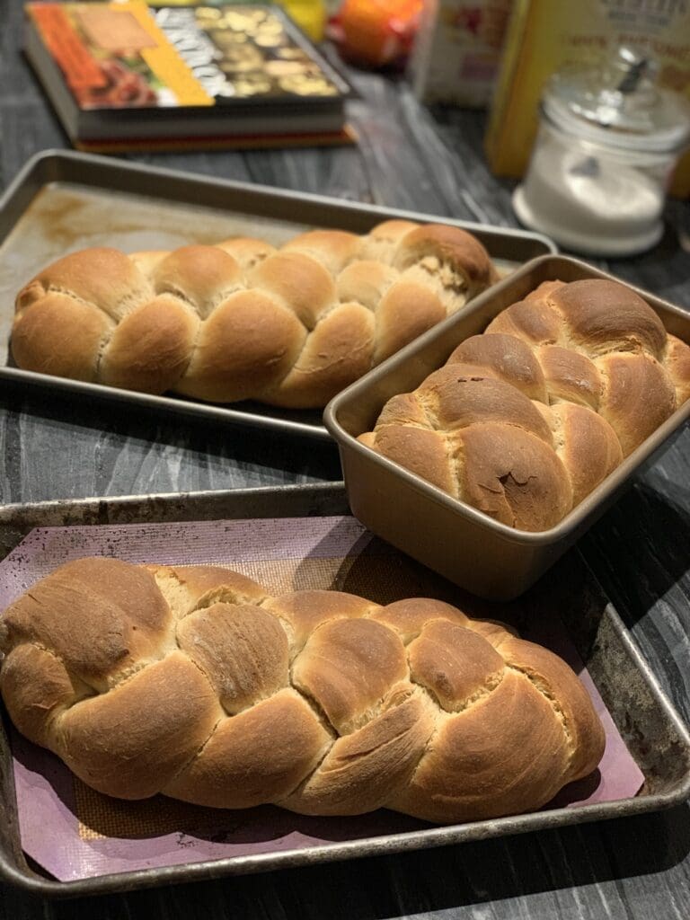 Three loaf pans with bread on them sitting on a table.