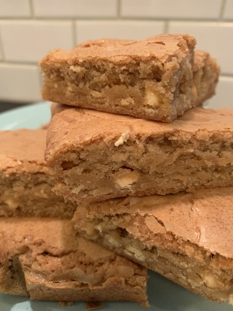 A stack of brownies with nuts on top.