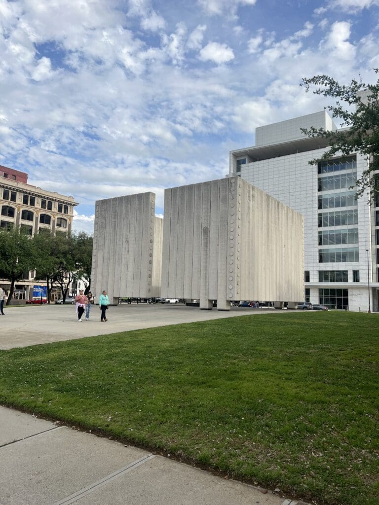 A grassy area with two large buildings in the background.